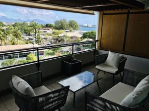a balcony with chairs and a table and a view of the ocean at Tipanie- Great 1bedroom in PPT, AC w pool & open view in Papeete
