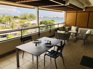 a table and chairs on a balcony with a view of the ocean at Tipanie- Great 1bedroom in PPT, AC w pool & open view in Papeete