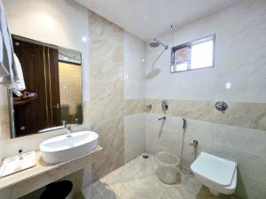 a white bathroom with a sink and a toilet at Kuber - Palace Premium # Restaurant- Lift and Free Parking Facilities - Fully Air Conditioning Premium Room in Puri