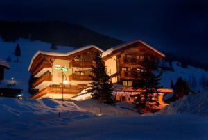 a large building in the snow at night at Hotel Dolomites Inn in Canazei