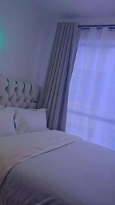 Un dormitorio con una cama blanca con una ventana. en Neriah paradise, en Nairobi
