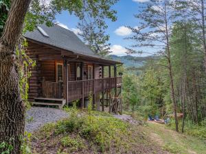 une cabane en rondins dans les bois avec une terrasse couverte dans l'établissement 1 bedroom with a loft and hot tub cabin 45 minutes to Asheville, à Marion