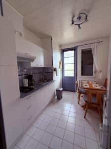 a kitchen with white cabinets and a table in it at Sea View in Quend-Plage