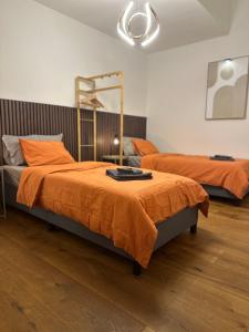 2 Betten mit orangefarbener Bettwäsche in einem Zimmer in der Unterkunft Topspot Wallis 30 min nach Zermatt oder SaasFee in Stalden