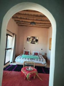 a bedroom with a bed and a table in a room at LA HACIENDA Agafay Desert 