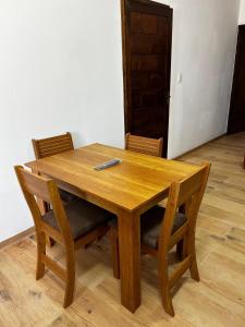 Una mesa de madera con sillas y un control remoto sobre ella. en Chuy Aparts 2, en Chuy