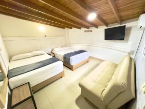 a bedroom with two beds and a couch and a tv at Hotel Estadio 80 in Medellín