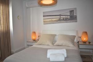 a bedroom with a white bed with two lamps at Zentral Gelegene Wohnung in Cómpeta