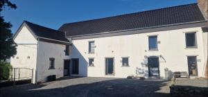a white brick building with a black roof at Chez fina in Ath