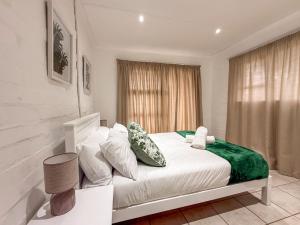 Gulls Nest في هيرمانوس: غرفة نوم بها سرير مع ملاءات ووسائد بيضاء