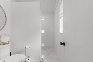 a white bathroom with a toilet and a shower at La Casita - Steps from 7th Ave in Tampa