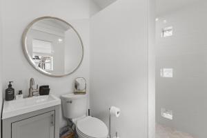 a white bathroom with a toilet and a mirror at La Casita - Steps from 7th Ave in Tampa +19 photos