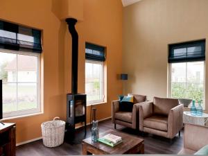 a living room with a fireplace and a couch and chairs at Detached house in Vlagtwedde with sauna in Vlagtwedde