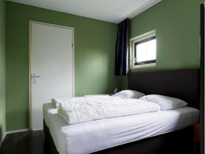 a bedroom with green walls and a bed with white sheets at Detached house in Vlagtwedde with sauna in Vlagtwedde