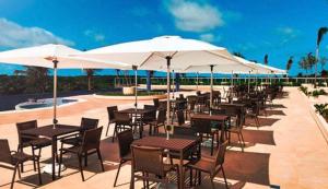 eine Reihe von Tischen und Stühlen mit Sonnenschirmen auf einer Terrasse in der Unterkunft Salinas Park Resort in Salinópolis + 3 Fotos