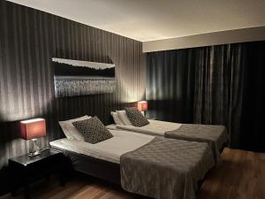 a bedroom with two beds and two lamps in it at Hotel Yöpuu in Kemi