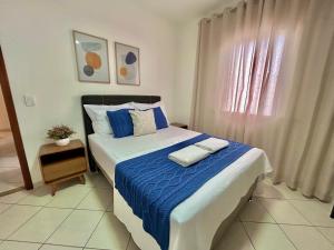 una camera da letto con un letto con lenzuola blu e una finestra di Apê charmoso a 2km do Centro - 4km do Pq Aquático ad Águas de Lindóia