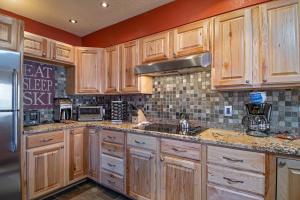 Overlook Athletic Club HeliportBase 9 Aprés Ski Condo: Stroll To Slopes, Downtown的厨房配有木制橱柜和不锈钢冰箱