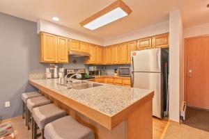 a kitchen with wooden cabinets and a white refrigerator at Lagoon Royal Townhome: Mountain Views Meet Modern Comforts in Frisco +26 photos