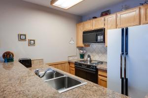 a kitchen with a refrigerator and a sink at River Mountain Lodge Peaks Trail Condo: Ski-In, Downtown Breck in Breckenridge
