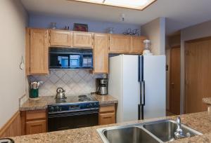 a kitchen with a white refrigerator and a sink at River Mountain Lodge Peaks Trail Condo: Ski-In, Downtown Breck in Breckenridge +20 photos