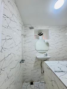 une salle de bain blanche avec lavabo et douche dans l'établissement Maison N 20, à Oulad Akkou