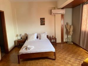 um quarto com uma cama com lençóis brancos e uma ventoinha em Residencial P&P em Mindelo