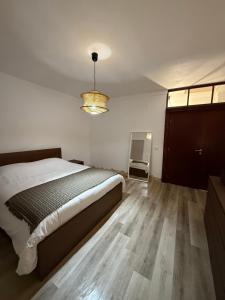 een slaapkamer met een groot bed en een kroonluchter bij Casa da Ti'nês in Bombarral