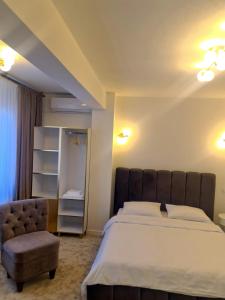 a bedroom with a large bed and a chair at Jolie Hotel in Craiova