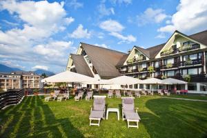 un gran edificio con sillas, mesas y sombrillas en Hotel Kompas en Bled