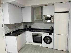 a kitchen with white cabinets and a washing machine at Olas del Sur Apartment in La Cala de Mijas