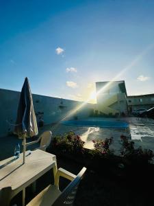 a patio with a table and an umbrella and a pool at Pousada e hostel Costa do Sol Coroa Vermelha in Porto Seguro