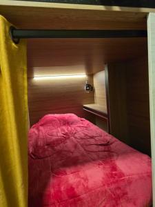 a small bedroom with a bed with a red blanket at Casa del Árbol Xochimilco in Oaxaca City