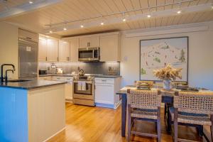 una cucina con mobili bianchi e un tavolo con sedie di Atelier Alpine - Modern 2BD Condo w/Baldy Views a Sun Valley