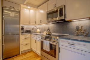 a kitchen with white cabinets and stainless steel appliances at Atelier Alpine - Modern 2BD Condo w/Baldy Views in Sun Valley