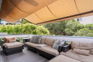 eine Terrasse mit einem Sofa, 2 Stühlen und einem Tisch in der Unterkunft Darling Del Mar Beach Cottage with Ocean Views in San Diego