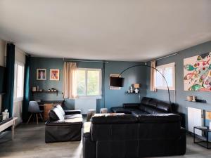 a living room with a black couch and blue walls at La Villa du Cap - indoor pool - billiards table in Fouesnant