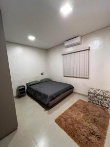 - une chambre avec un lit, un canapé et un tapis dans l'établissement 2 Quartos, sala e 1 banheiro próximos à Universidade Federal de Rondonópolis- UFR, à Rondonópolis