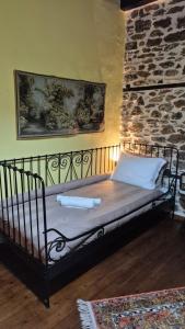 a metal bed in a room with a stone wall at Αρχοντικό Πανόραμα in Melívoia