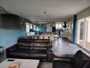 a living room with a leather couch and a table at La Villa du Cap - indoor pool - billiards table in Fouesnant