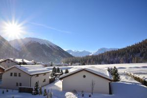 ein schneebedecktes Feld mit Gebäuden und Bergen in der Unterkunft Chesa Filomela in Bever