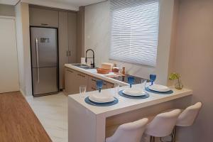 a kitchen with a table with plates and wine glasses at Lindo e Moderno na praia do Gonzaga c/ar in Santos