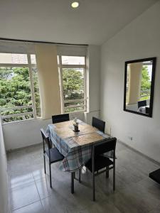 Un comedor con mesa y sillas y ventanas. en Apartaestudios centro ibague, en Ibagué