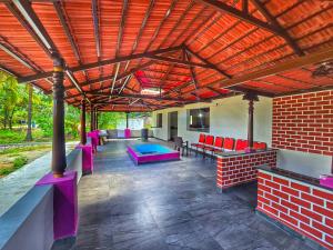 a covered patio with a pool and red chairs at Palms & Peace - A Serene getaway with hill view By Shivalaya in Coimbatore