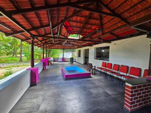 a patio with red chairs and a blue table at Palms & Peace - A Serene getaway with hill view By Shivalaya in Coimbatore