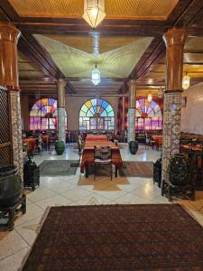 une grande pièce avec des tables et des vitraux dans l'établissement Chez Ali, à Zagora