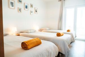 une chambre avec trois lits avec des serviettes dessus dans l'établissement Arrifana Surf Camp, à Aljezur