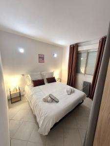 a bedroom with a large white bed with towels on it at rez de villa confort & grand extérieur in Furiani