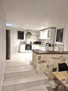 a kitchen with white cabinets and a stone floor at rez de villa confort & grand extérieur in Furiani