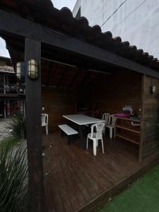 a wooden deck with a table and chairs on it at Pousada Campus Rosa in Praia do Rosa